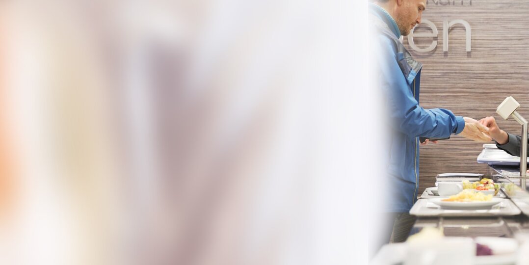 Dussmann service employee cashes up food serving area 